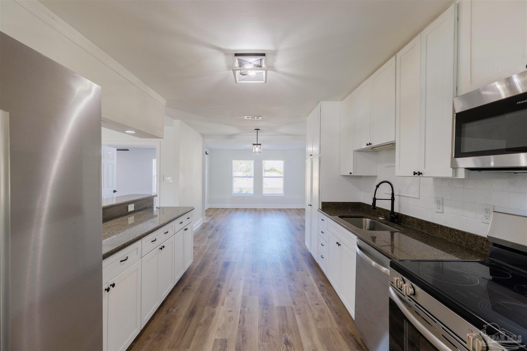 2115 Stallion Road Cantonment, FL 32533 - Photo 22 of 70 a large kitchen with granite countertop a stove top oven a sink a counter space and cabinets