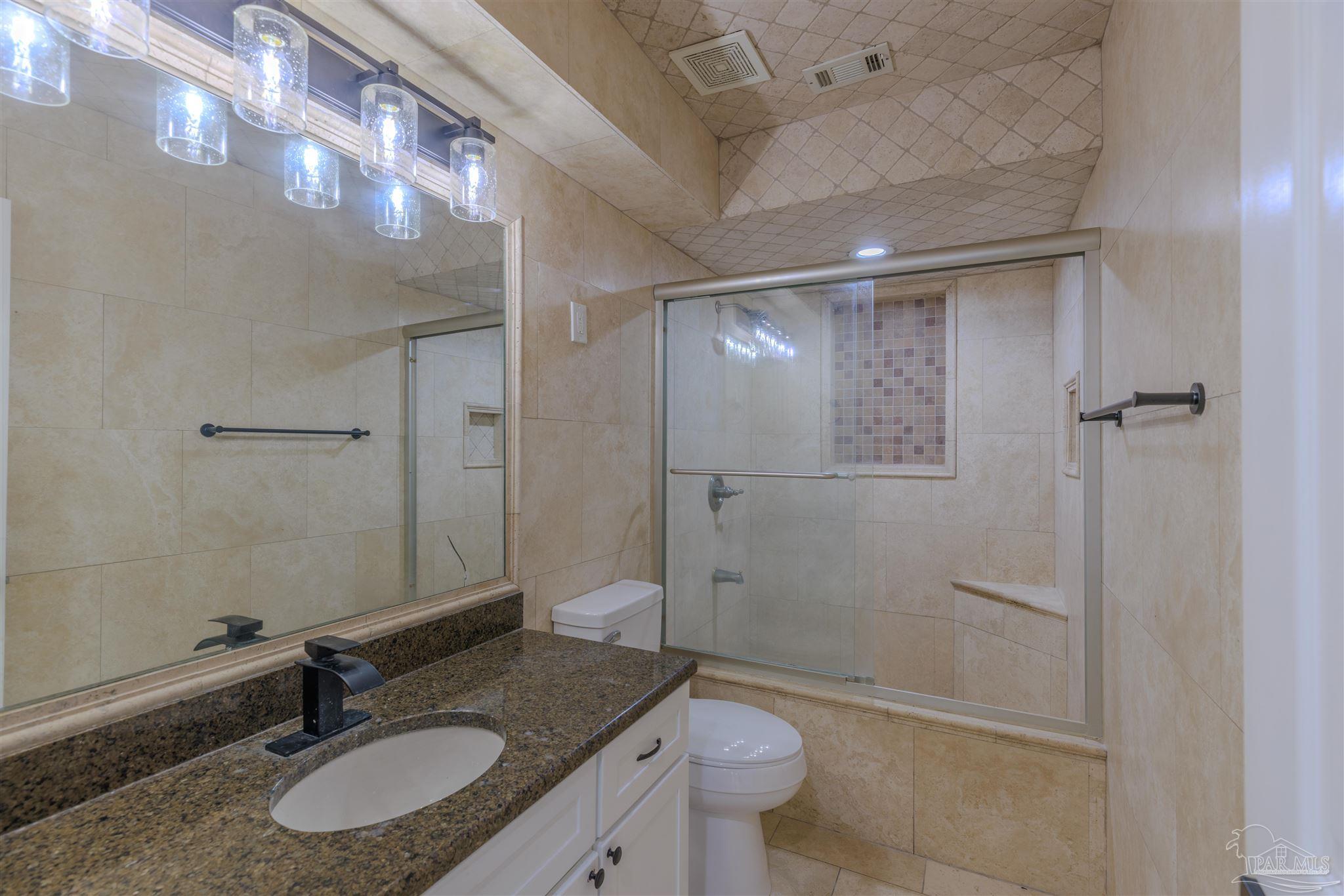2115 Stallion Road Cantonment, FL 32533 - Photo 29 of 70 a bathroom with a granite countertop sink toilet a mirror and shower