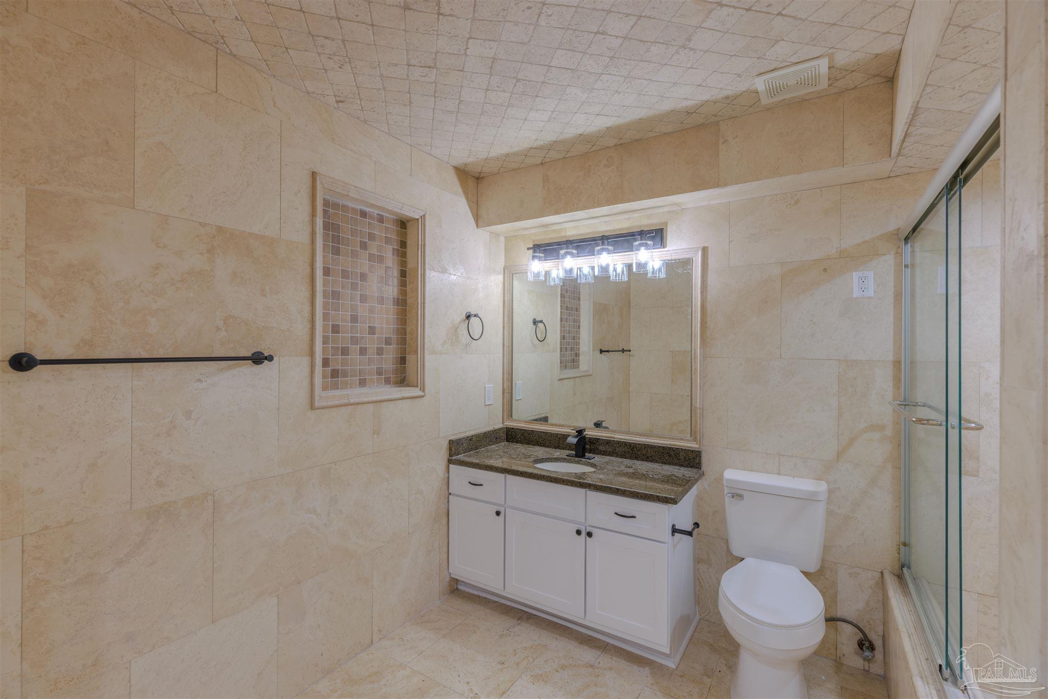 2115 Stallion Road Cantonment, FL 32533 - Photo 38 of 70 a bathroom with a granite countertop sink a toilet a mirror and shower