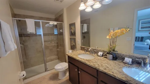 a bathroom with a granite countertop sink a toilet a mirror and shower