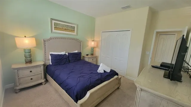a bedroom with a bed and a flat tv screen on the dresser