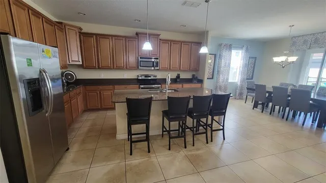 a kitchen with stainless steel appliances granite countertop a table chairs and a refrigerator