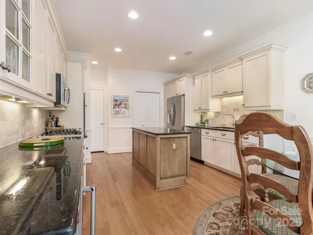 a kitchen with a refrigerator a stove top oven a sink dishwasher and white cabinets with wooden floor