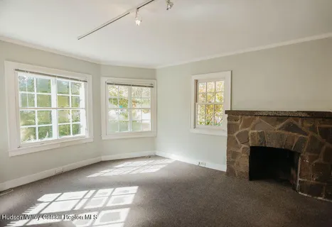 an empty room with windows and fireplace