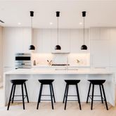 a kitchen with stainless steel appliances kitchen island granite countertop a table chairs in it and white cabinets