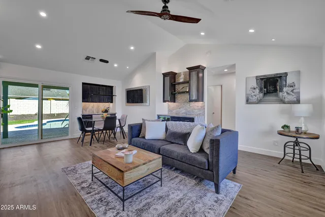 a living room with furniture kitchen area and a wooden floor