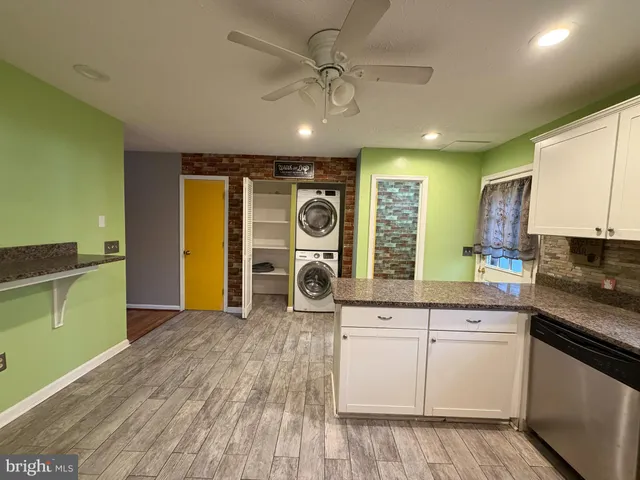 a kitchen with a sink dishwasher and white cabinets with wooden floor
