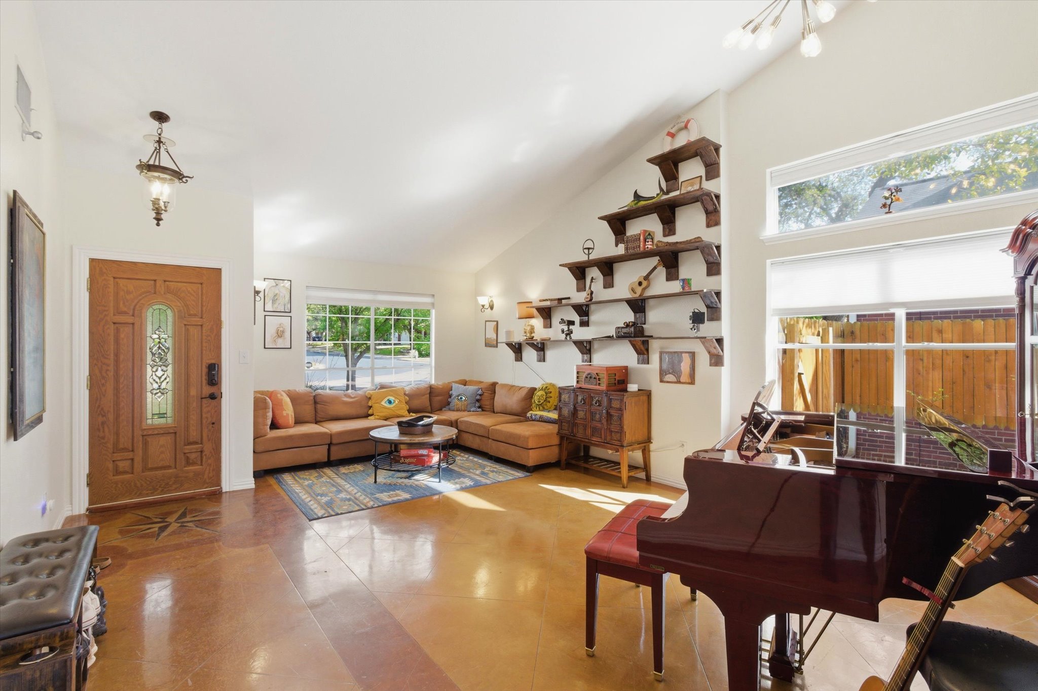 8920 West Hove Loop Austin, TX 78749 - Photo 2 of 39 Vaulted ceiling living area featuring a decorative entry door with stained glass, polished concrete flooring, a custom built-in shelving system, and large windows with privacy blinds