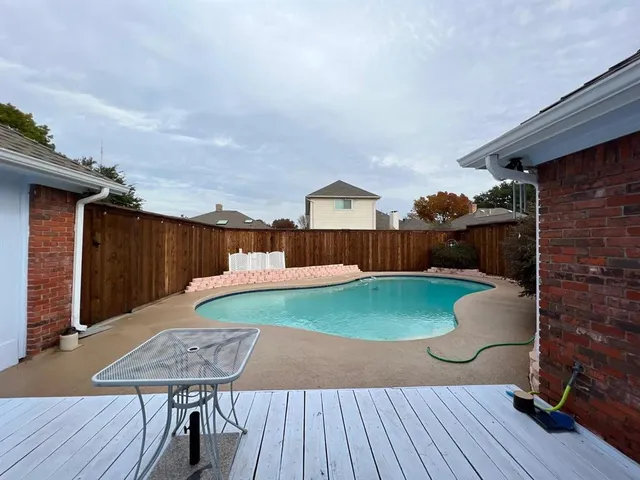 a view of a patio with table and chairs with wooden floor and fence