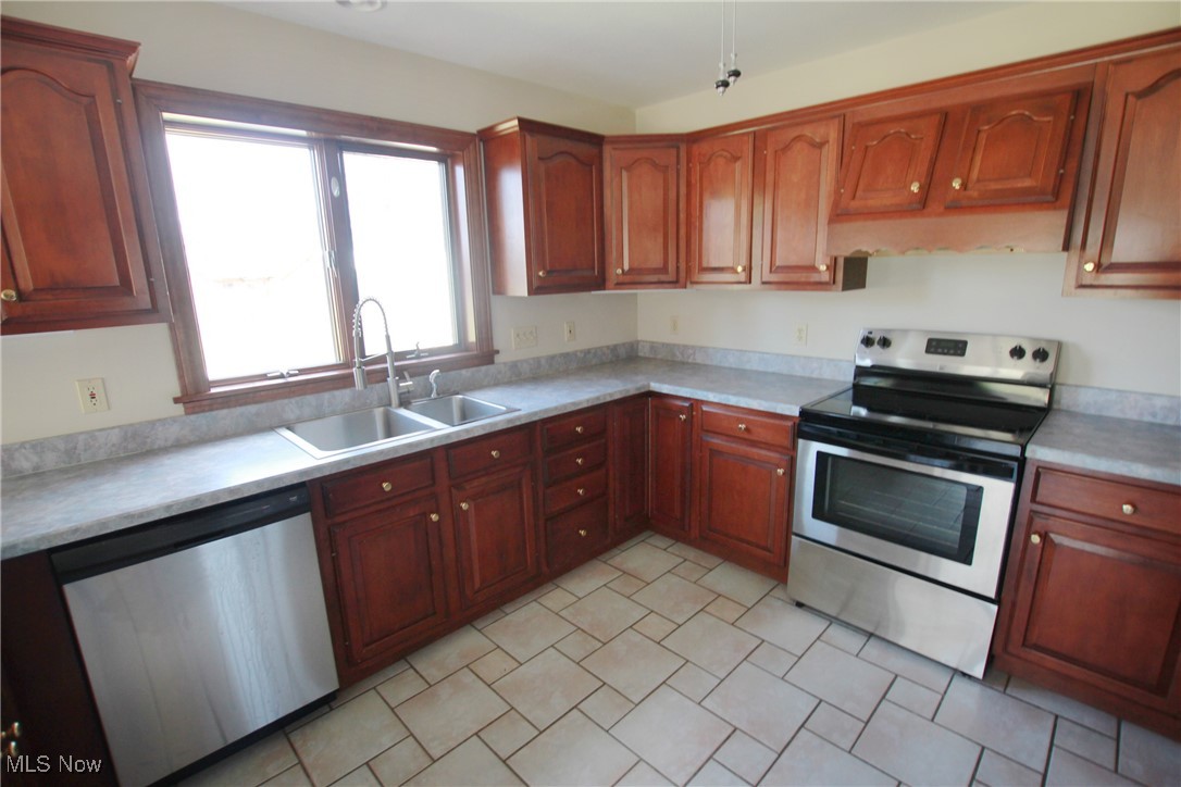 1031 Georgetown Road Salem, OH 44460 - Photo 18 of 31 Kitchen with appliances with stainless steel finishes, brown cabinets, light countertops, and a sink