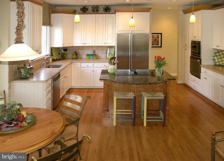 1300 Stamford Way Reston, VA 20194 - Photo 10 of 30 a kitchen with stainless steel appliances kitchen island granite countertop a table chairs and a refrigerator