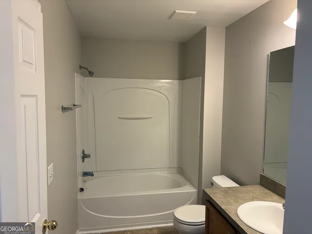 a bathroom with a granite countertop toilet and a tub