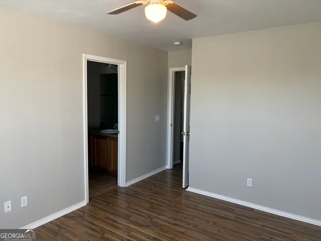 a view of an empty room with wooden floor and closet