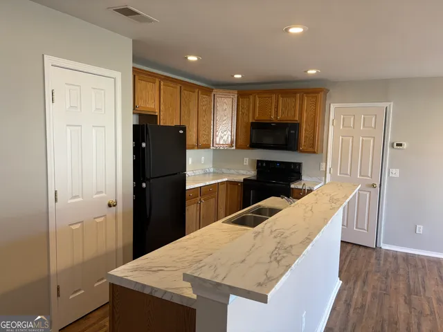 a kitchen with granite countertop wooden cabinets a refrigerator and a sink