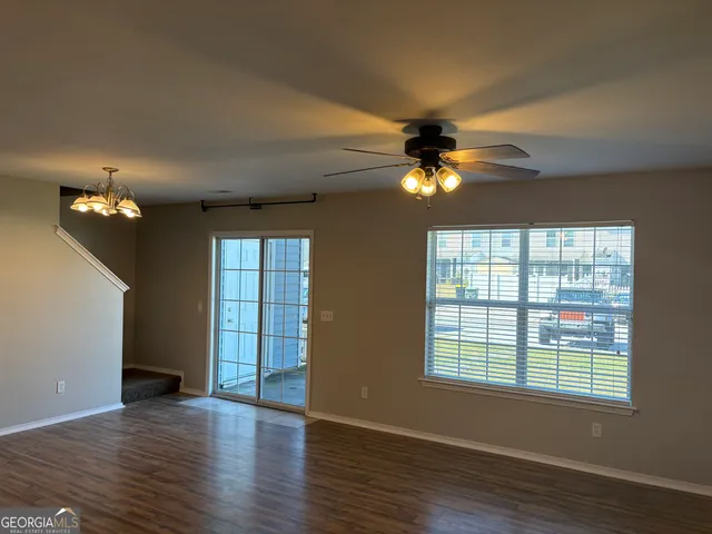 a view of an empty room with a window and wooden floor