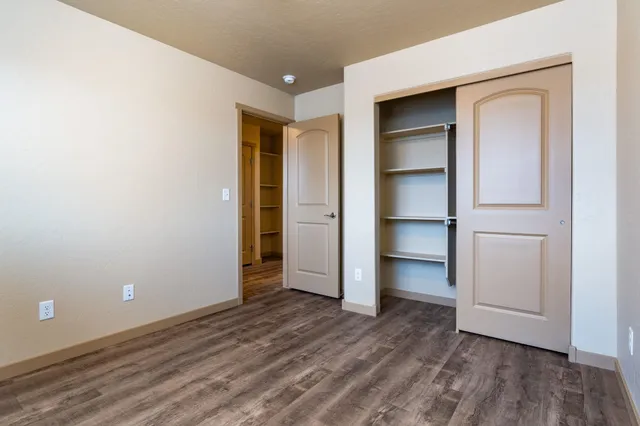 a view of an empty room with closet and wooden floor