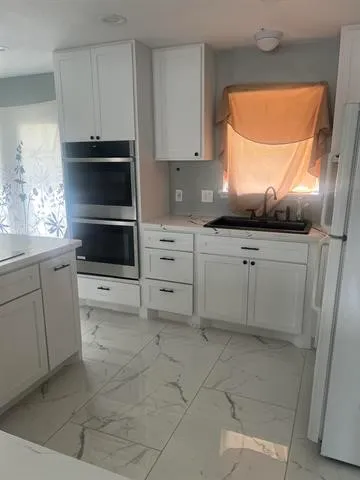 a kitchen with white cabinets and appliances