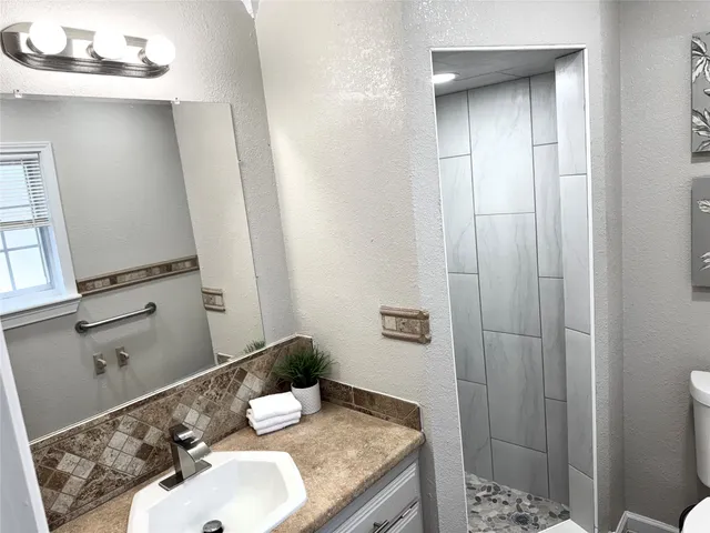 a bathroom with a granite countertop sink a toilet and shower curtain
