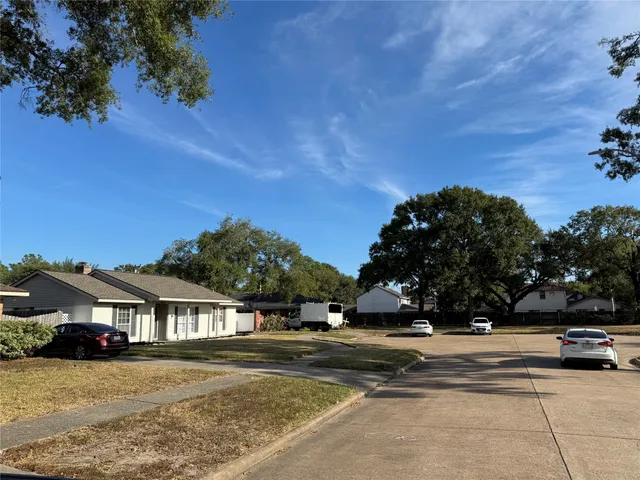 a view of a white house next to a yard with big trees