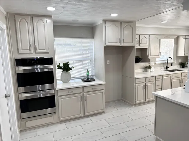 a kitchen with a sink white cabinets and appliances