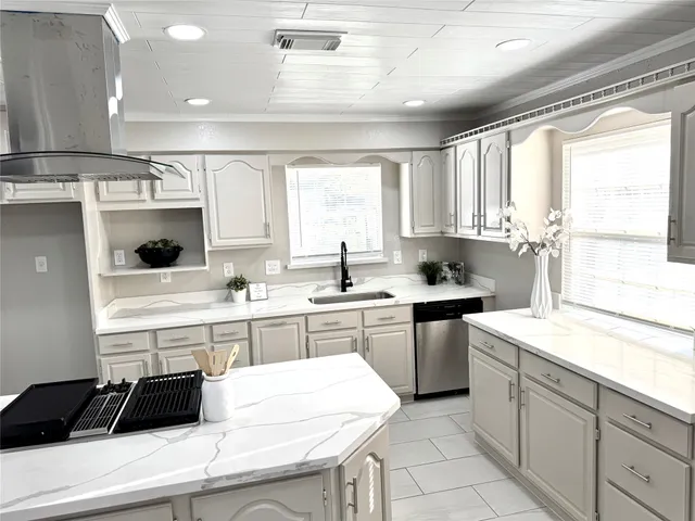 a kitchen with a sink a stove and white cabinets