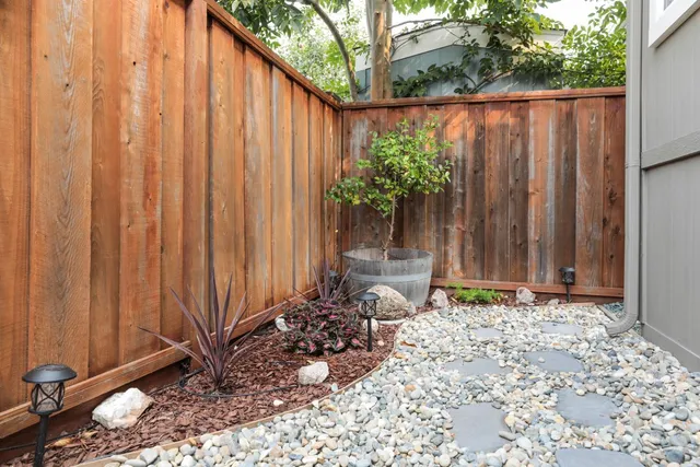 a view of a backyard with potted plants and wooden fence