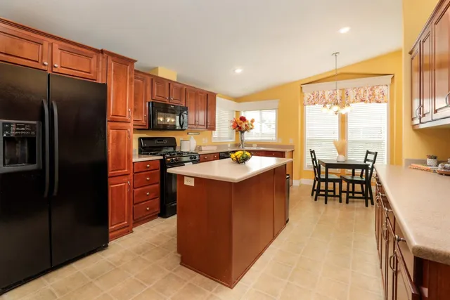 a kitchen with stainless steel appliances granite countertop a stove top oven a sink and a refrigerator