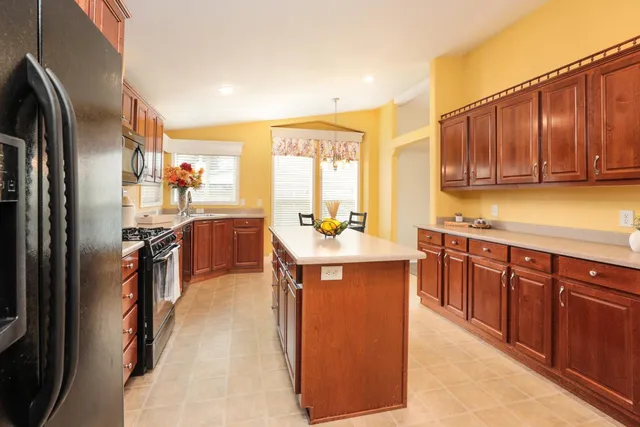 a kitchen with stainless steel appliances granite countertop a refrigerator a sink a stove and island