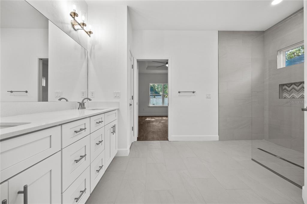 1086 Southwest 67th Drive Gainesville, FL 32607 - Photo 11 of 37 a spacious bathroom with a double vanity sink a large mirror a shower and vanity