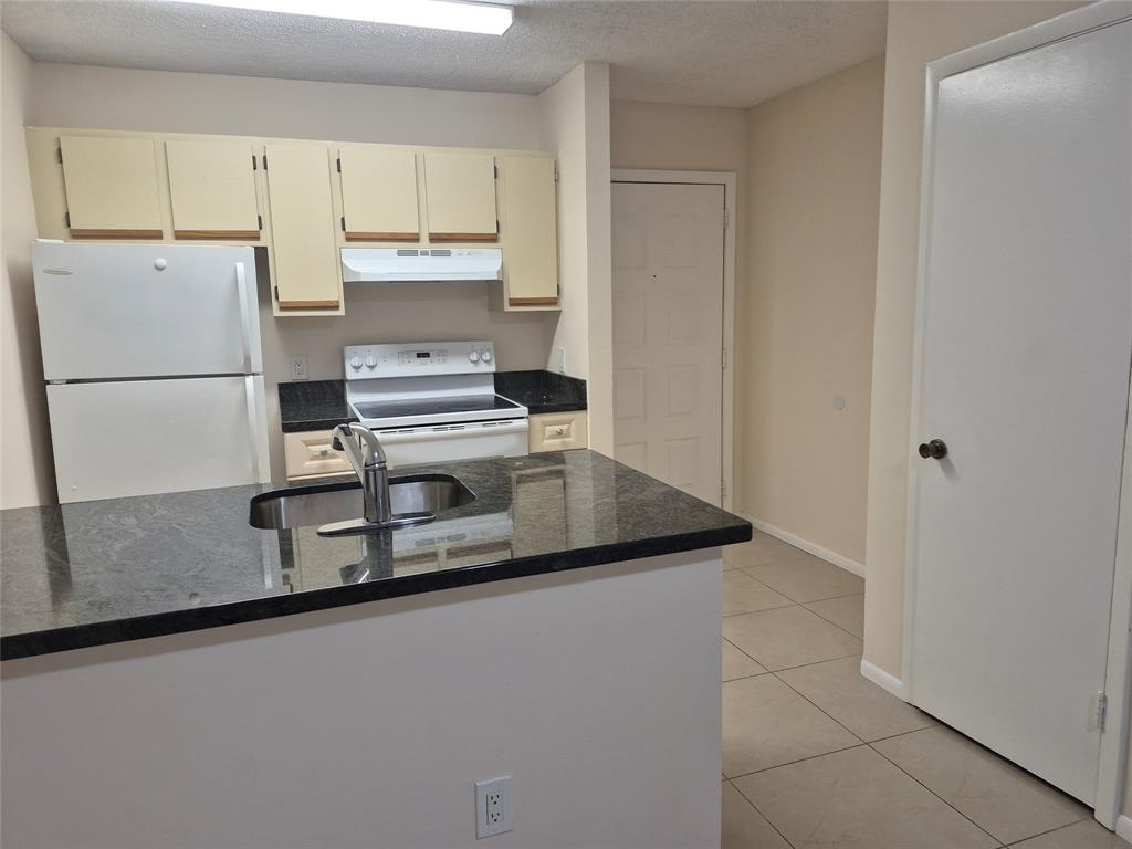 4481 West McNab Road, Unit 10 Pompano Beach, FL 33069 - Photo 7 of 16 a kitchen with a refrigerator sink and cabinets