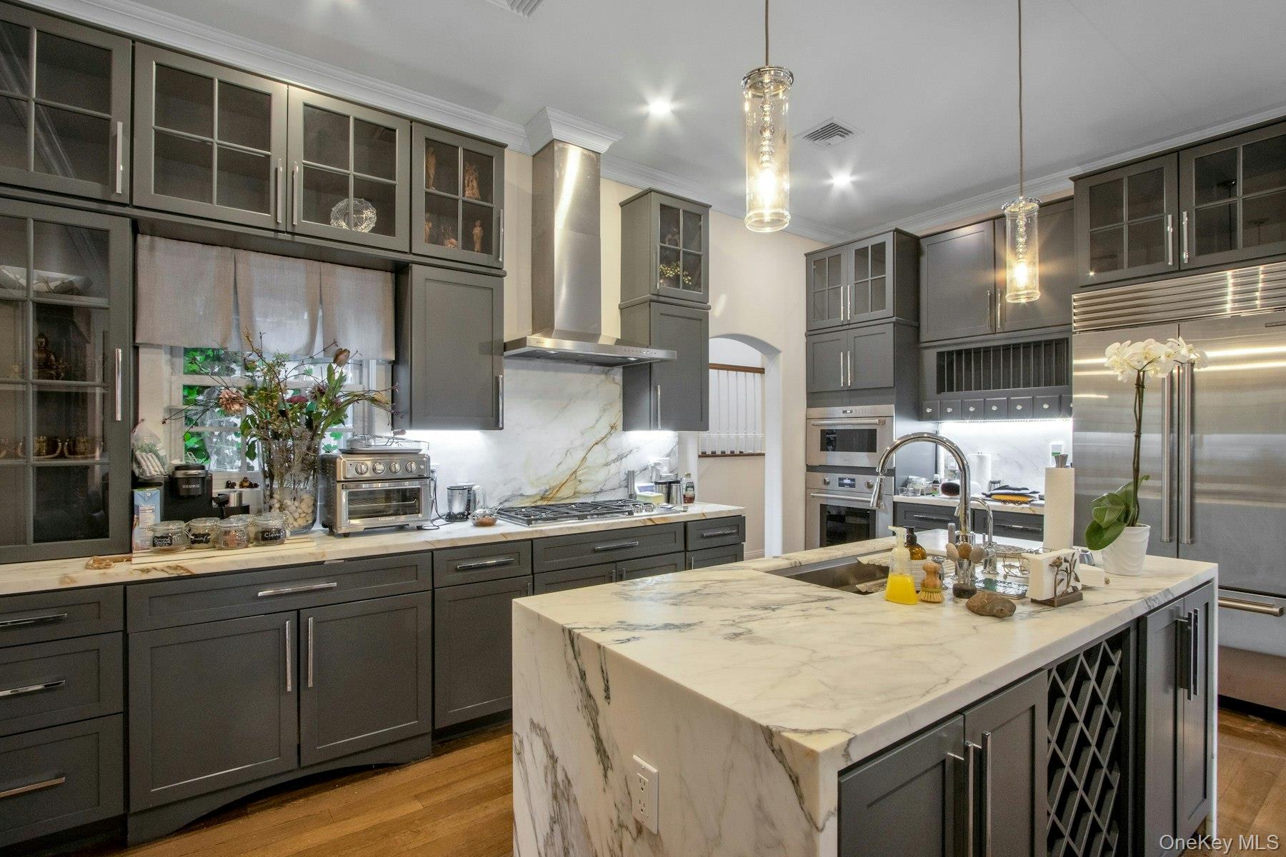 129 Washington Spring Road Palisades, NY 10964 - Photo 9 of 44 Kitchen featuring wall chimney exhaust hood, stainless steel appliances, light stone counters, an island with sink, and decorative light fixtures