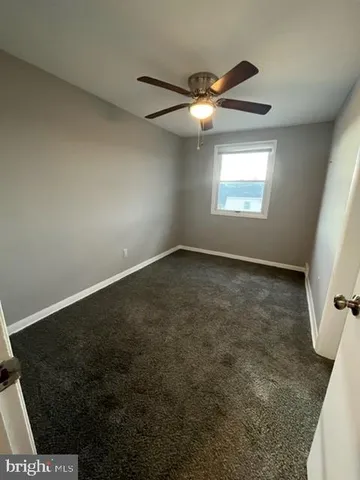 an empty room with windows and ceiling fan