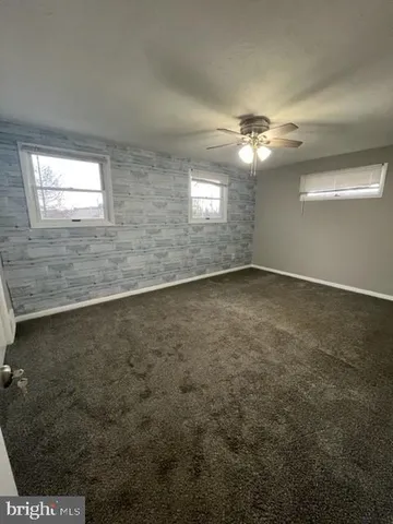 en empty room with windows and ceiling fan