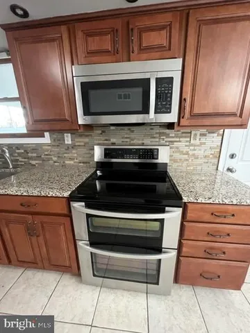 a kitchen with granite countertop a stove and a microwave cabinets