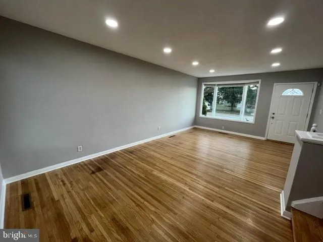 an empty room with wooden floor and windows