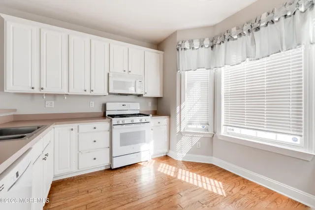 a kitchen with granite countertop white cabinets and white appliances