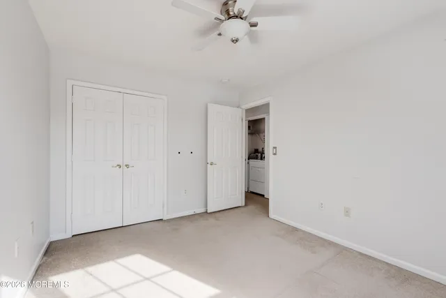 an empty room with a ceiling fan and carpet
