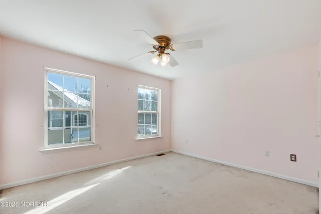 an empty room with windows and fan