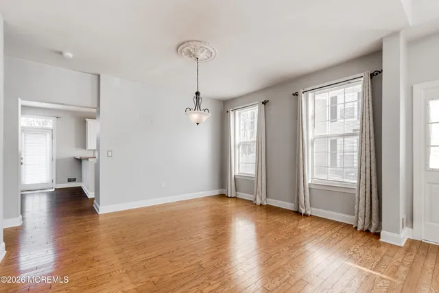 a view of empty room with wooden floor and window