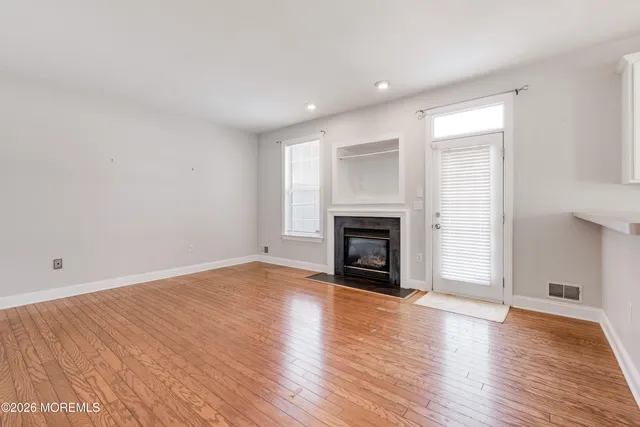 a view of empty room with wooden floor and fireplace