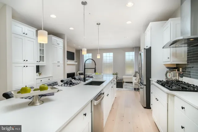a kitchen with a sink stove and white cabinets with wooden floor