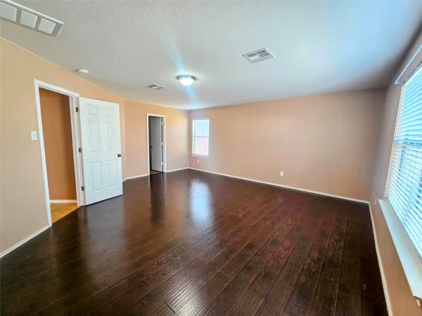 an empty room with wooden floor and windows