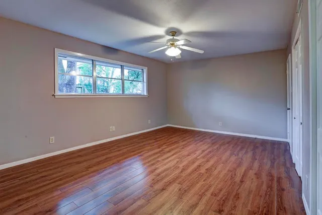 a view of an empty room with wooden floor and a window