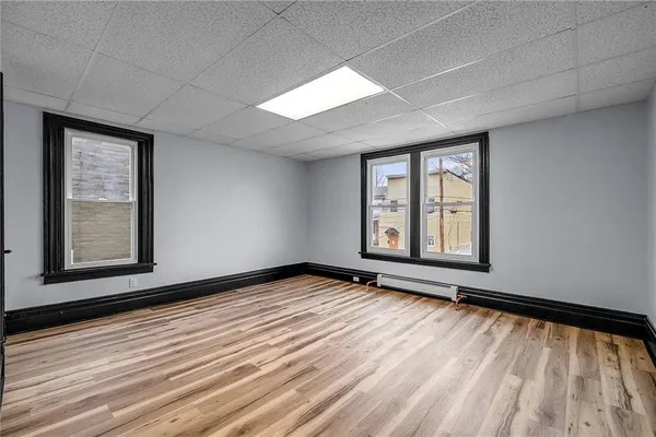 a view of an empty room with a window and wooden floor