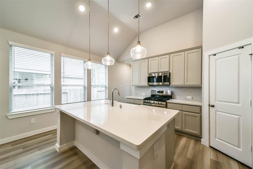 a large white kitchen with a large window a sink and stainless steel appliances