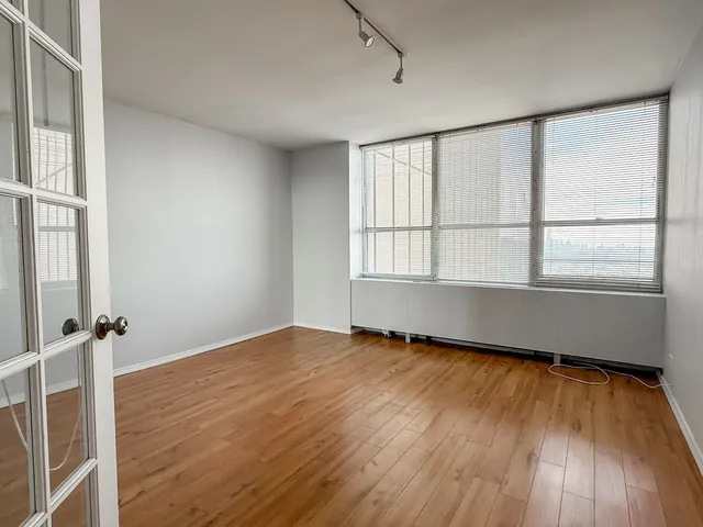 a view of an empty room with wooden floor and a window
