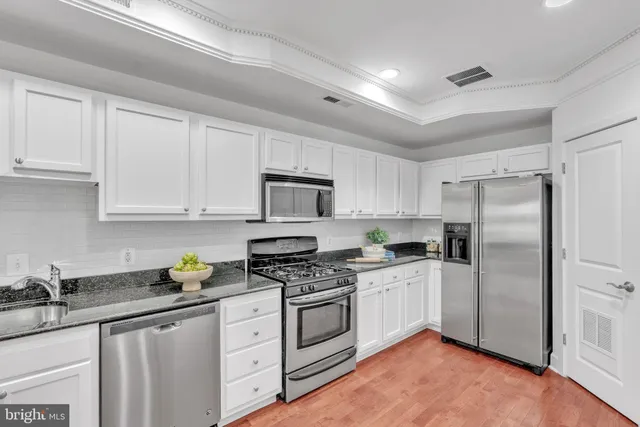 a kitchen with white cabinets stainless steel appliances and a sink
