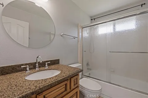 a bathroom with a granite countertop sink toilet a mirror and shower