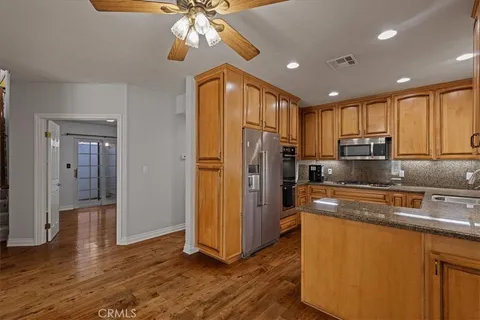 a kitchen with stainless steel appliances granite countertop a refrigerator a stove top oven a sink and dishwasher with wooden floor