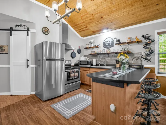 a kitchen with stainless steel appliances granite countertop a refrigerator a stove and a sink with wooden floor